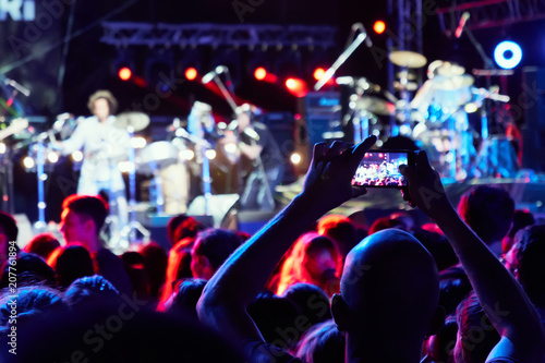 Hand with a smartphone records live music festival, live concert, happy youth