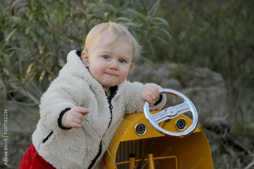Petit bébé garçon dans son jardin avec la voiture. jeux d'enfants