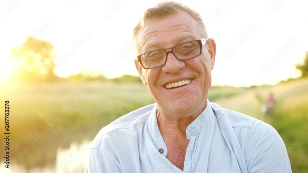 Carefree retired man smiling looking at camera. Portrait of an elderly man wearing glasses. Happy holidays. Father's Day Carefree retired man smiling looking at camera. Portrait of an elderly man wearing glasses. Happy holidays. Father's Day