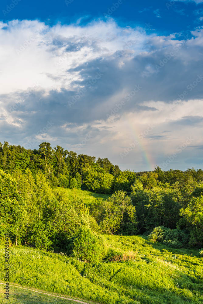 Beautiful landscape with forest and hills and a rainbow in the sky