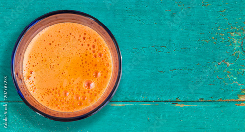 Carrot juice - colorful healthy drink in glass on old blue wooden table. Top view.. Copy space.
