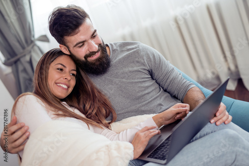 Happy young couple with laptop in living room