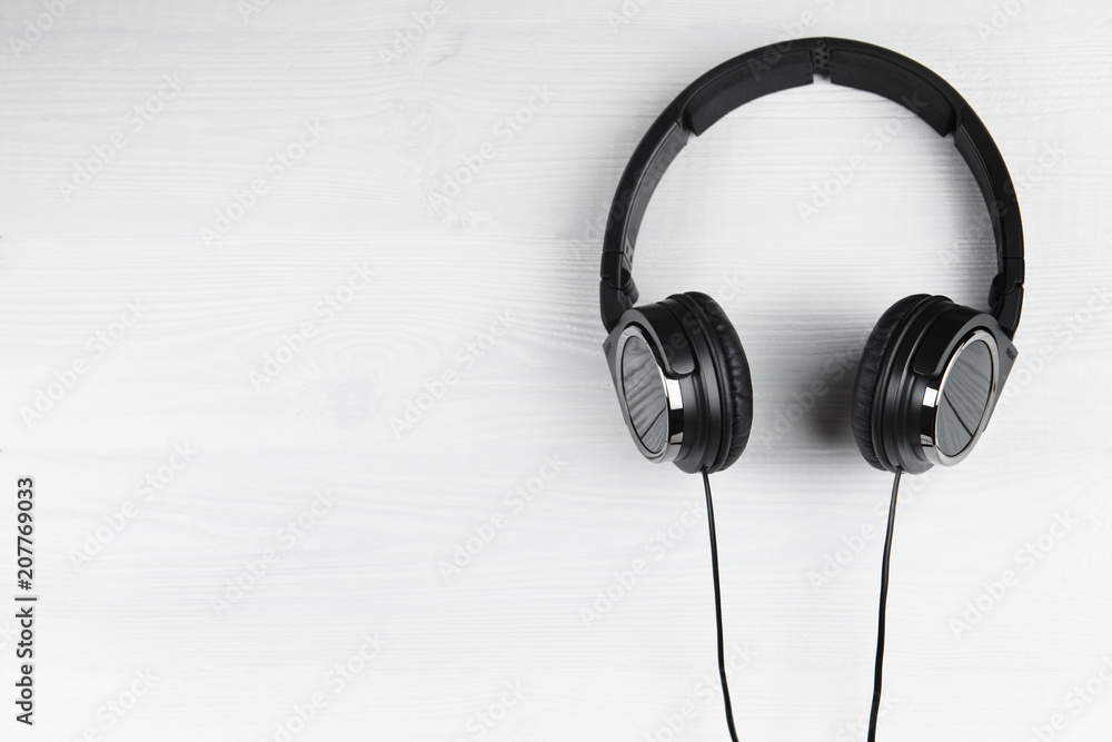 Black headphones on white wooden background. Music concept. Black headphones on white wooden background. Music concept.
