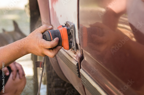 Male hand using a palm sander on a truck  to remove paint photo