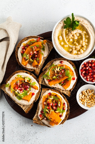 tasty bruschettes with hummus, baked pumpkin and arugula pesto on the table. vegan healthy food