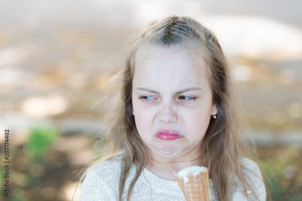 Sweet tooth girl child with white ice cream in waffle cone. Kid girl with ice cream cone in hand. Summer treats concept. Girl sweet tooth on disgusted face eats ice cream, light background Sweet tooth girl child with white ice cream in waffle cone. Kid girl with ice cream cone in hand. Summer treats concept. Girl sweet tooth on disgusted face eats ice cream, light background
