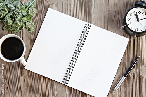 Still life, business, planning or working concept : Open notebook with blank pages, coffee cup and clock on wooden desk table, top view or flat lay with copy space ready for adding or mock up