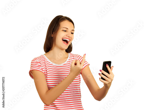 The spiteful smiling girl shows the middle finger in the phone. Fuck you sign. emotional girl isolated on white background photo