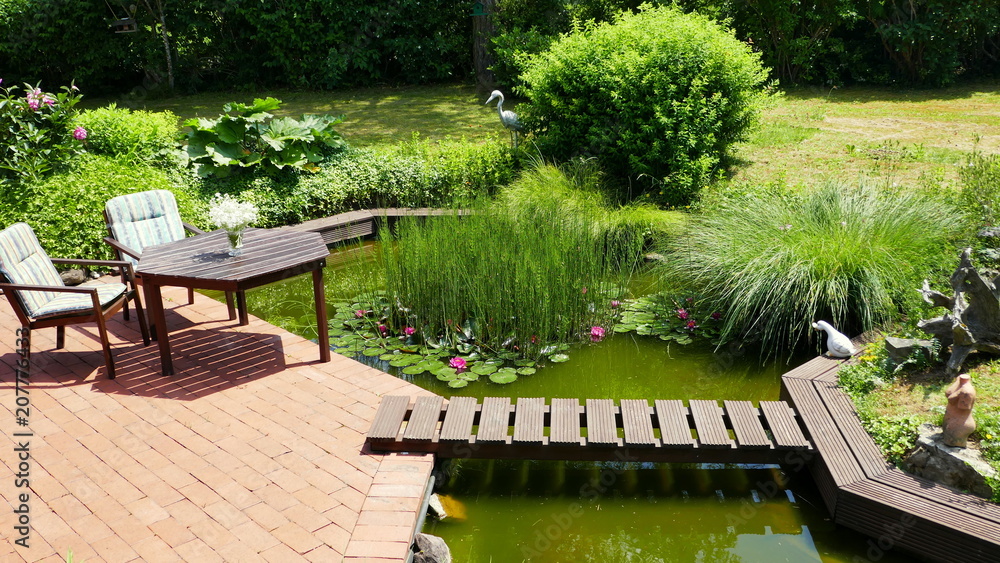 attraktiver naturbelassener Teich an rote Terrasse angrenzend mit