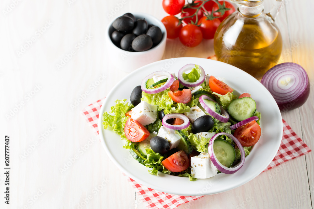Fresh Greek salad made of cherry tomato, ruccola, arugula, feta, olives, cucumbers, onion and spices. Caesar salad in a white bowl on wooden background. Healthy organic diet food concept. Fresh Greek salad made of cherry tomato, ruccola, arugula, feta, olives, cucumbers, onion and spices. Caesar salad in a white bowl on wooden background. Healthy organic diet food concept.