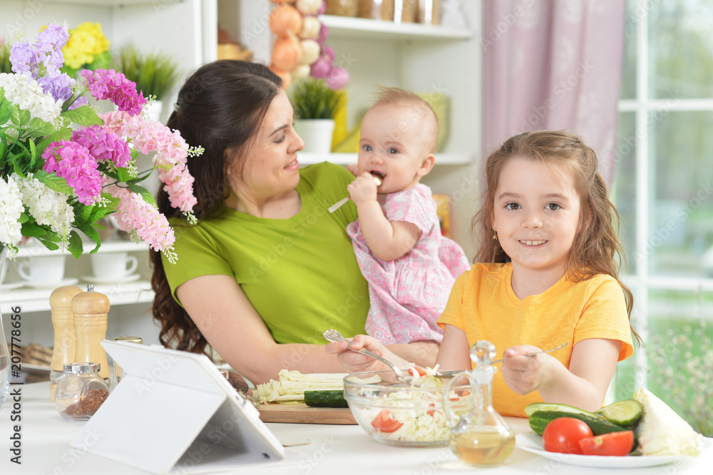 Cute little girl eating fresh salad at kitchen table Cute little girl eating fresh salad at kitchen table