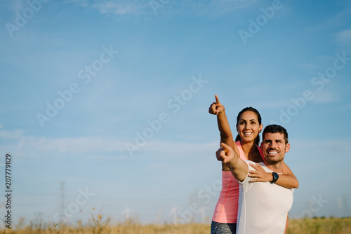 Couple of young man and woman embracing and pointing to the sky.