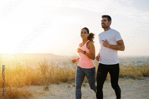 Two athletes running at sunset. Man and woman training together. photo