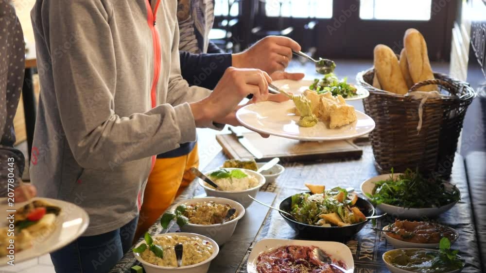 Brunch food layout in restaurant people hands put various dishes on plates Brunch food layout in restaurant people hands put various dishes on plates