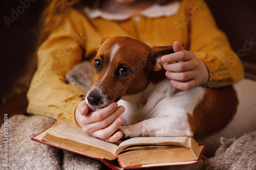 Girl and her friend dog jack russell reading the book.