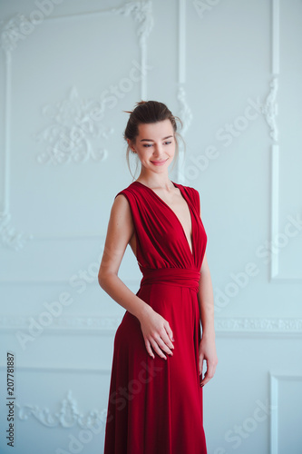 Beauty brunette model woman in evening red dress. Beautiful fashion luxury makeup and hairstyle. Seductive girl silhouette in classic interior.