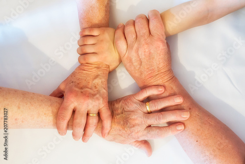 Hände mehrerer Generationen greifen ineinander.