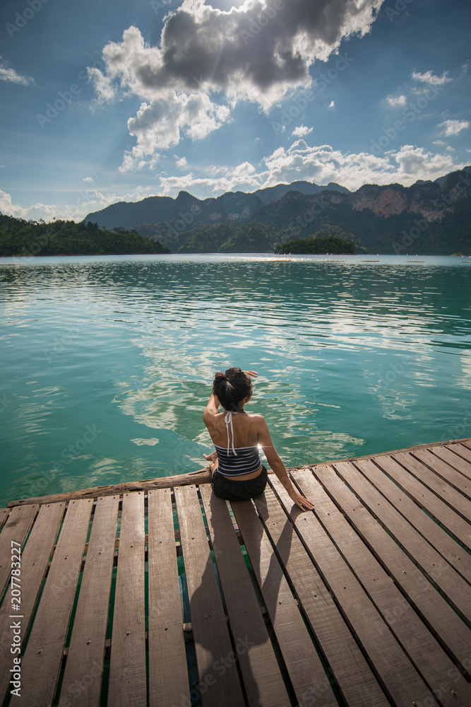 Woman relaxing on the pier lake side.