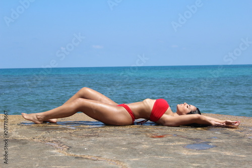 Beautiful woman posing at the beach with a red bikin