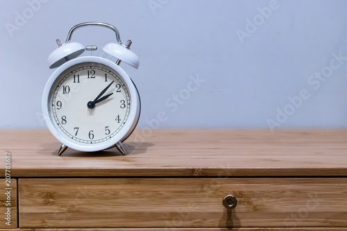White alarm clock on wooden desk