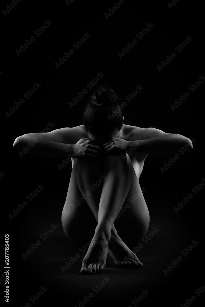 Fototapeta premium Art nude, perfect naked body, sexy woman sitting on dark background, black and white studio shot