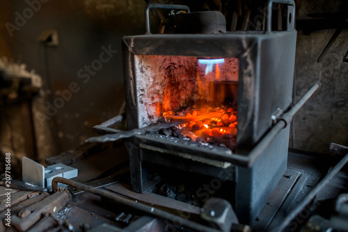 Blacksmith furnace with red hot metal workpiece.