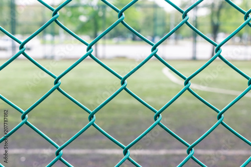 Green wire fence and football field on background
