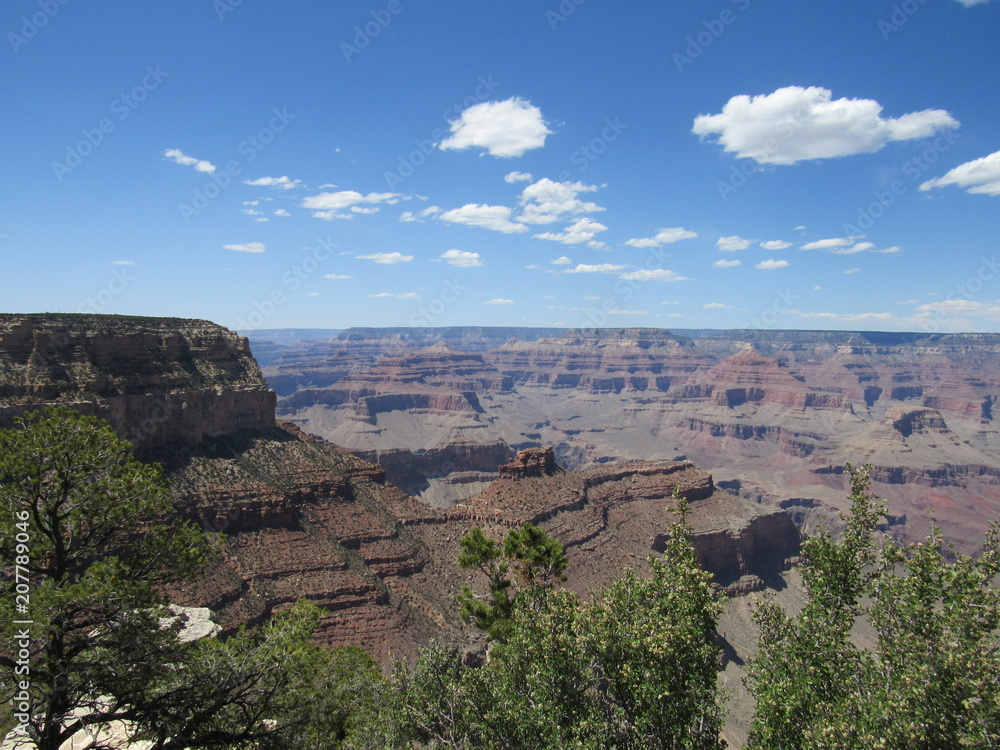 Views of the Grand Canyon on a sunny day with blue sky and clouds, as seen from the South Rim Trail