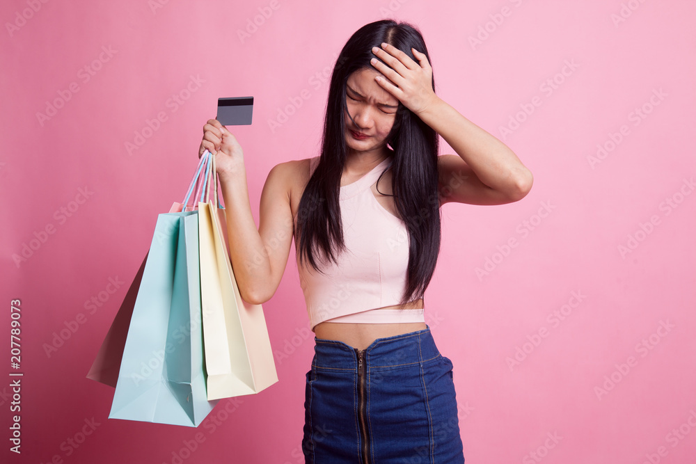 Unhappy young Asian woman with shopping bags and credit card. Unhappy young Asian woman with shopping bags and credit card.
