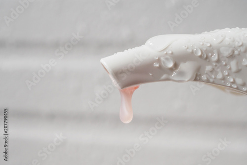 Water drop on liquid soap dispenser pump during bath time