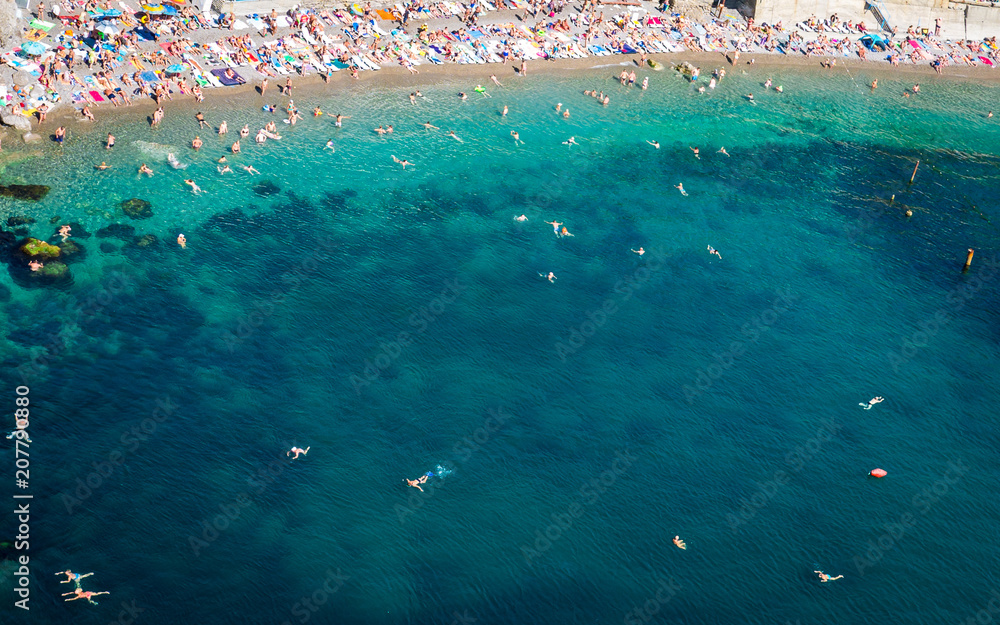 The top view and the beach. View from the high rocky shore. Azure-blue clear water. People swim in the beach. Black sea, Crimea