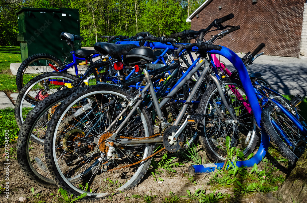 Right side view of crowded blue bike rack with deserted biycycles