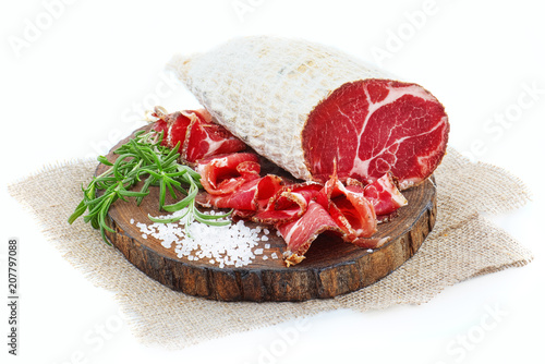 Sliced cured coppa with a sprig of rosemary. photo