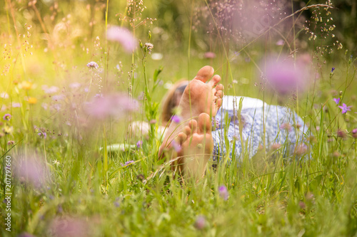 Junges Mädchen liegt entspannt in Blumenwiese, Füße