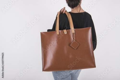 Girl is holding brown leather bag for mockup blank template isolated on gray background.
