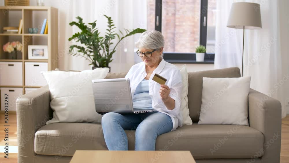 technology, online shopping and people concept - happy senior woman in glasses with laptop computer and credit or bank card at home technology, online shopping and people concept - happy senior woman in glasses with laptop computer and credit or bank card at home