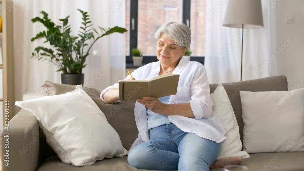 age, leisure and people concept - happy senior woman writing to notebook or diary at home age, leisure and people concept - happy senior woman writing to notebook or diary at home