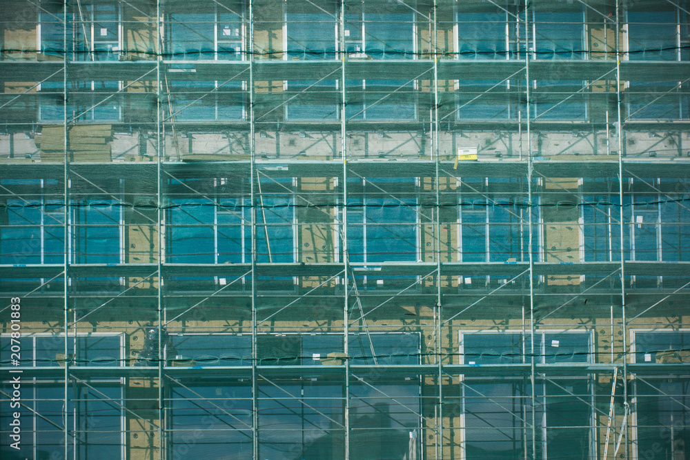 Unfinished cement building with shading net covered at a construction site in summer