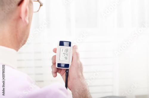 Man read measurement results from personal digital blood pressure monitor