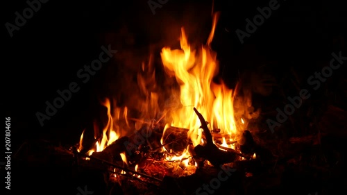 Video footage of a burning and sparking campfire at night with burning woods in 4K resolution.
