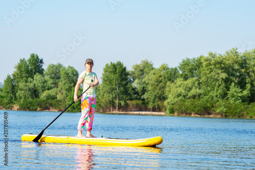 Adult woman is floating on a SUP board