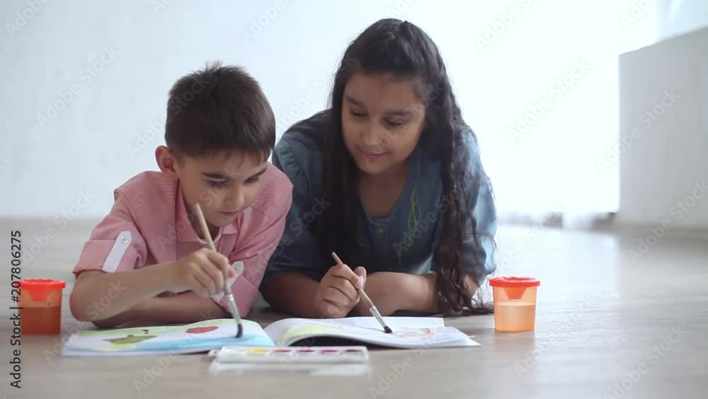 Happy little brother and sister paint with paint in the album lying on the floor and smile. Overall plan. HD Happy little brother and sister paint with paint in the album lying on the floor and smile. Overall plan. HD