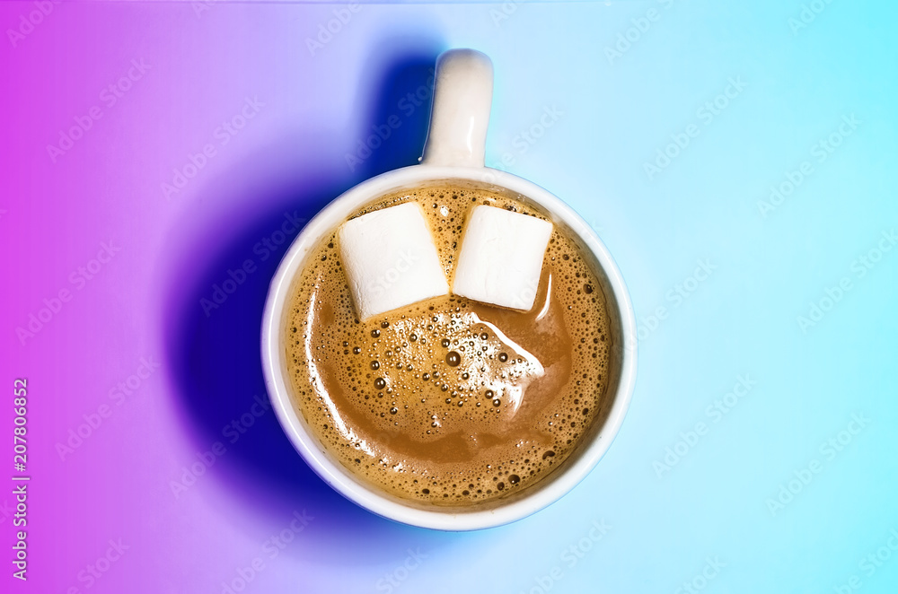a mug of hot coffee with marshmallows. marshmallow like eyes. smile in the coffee. turquoise background a mug of hot coffee with marshmallows. marshmallow like eyes. smile in the coffee. turquoise background