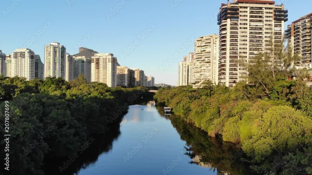 Drone aerial Hyperlapse of Marapendi canal in Barra da Tijuca on a summer day, with a boat slowly traveling along river. Tall residential skyscrapers on both sides, with green vegetation Drone aerial Hyperlapse of Marapendi canal in Barra da Tijuca on a summer day, with a boat slowly traveling along river. Tall residential skyscrapers on both sides, with green vegetation