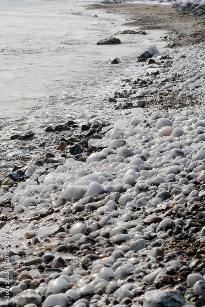 Ice covered stones with smooth white ice near water or sea at winter Ice covered stones with smooth white ice near water or sea at winter