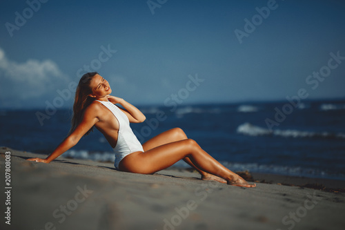 Young woman posing on the beach in a white swimsuit © djile