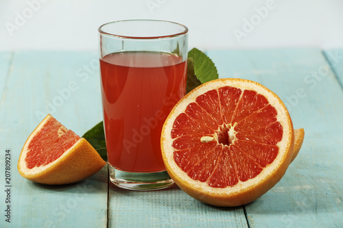 Grapefruit juice and fresh grapefruit on a wooden background. Fresh grapefruit juice in a glass bowl.