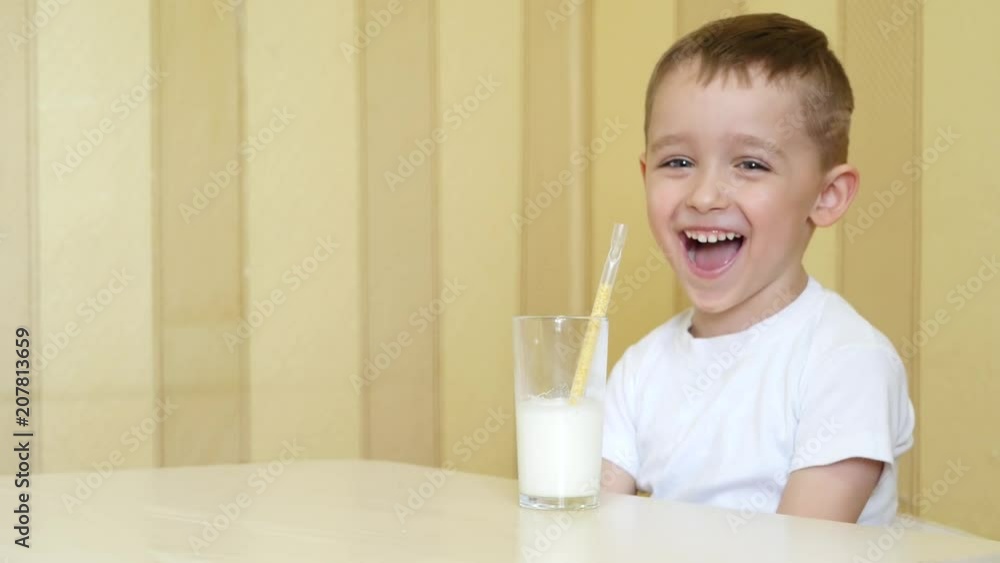 The baby is served milk in a glass with a straw. The child is happy. The baby is served milk in a glass with a straw. The child is happy.