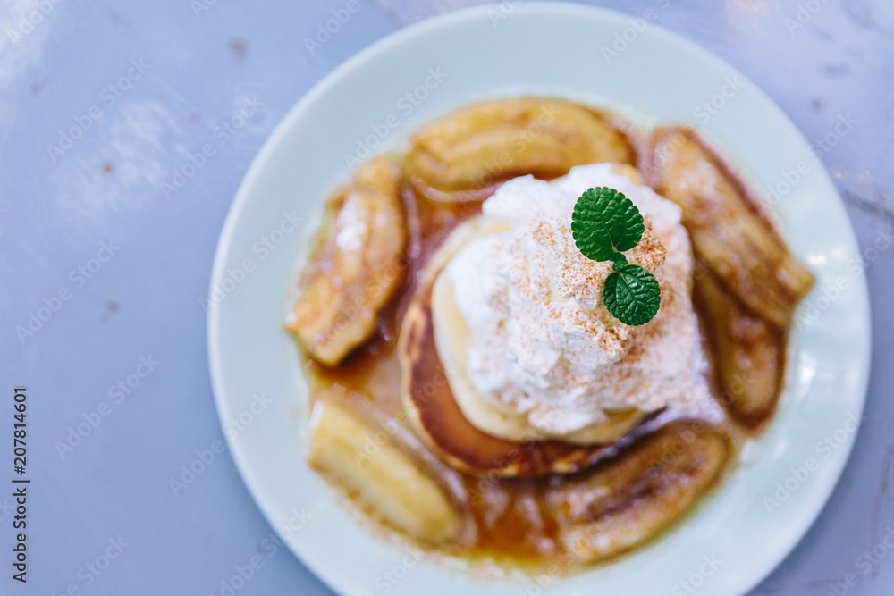 Top view of Pancakes with caramel-banana syrup topping with whip cream and mint leaves. Top view of Pancakes with caramel-banana syrup topping with whip cream and mint leaves.