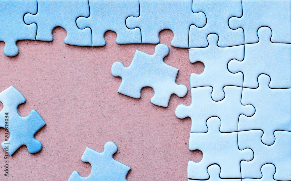 Connected pieces of blue one-color puzzle with three disconnected pieces on pink background. Closeup. Connected pieces of blue one-color puzzle with three disconnected pieces on pink background. Closeup.